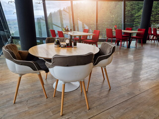 Tables and chairs set in modern cafe minimalistic interior design with big window and hanging ceiling lamps