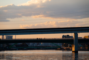 夕暮れ空の下で橋を渡る人達
