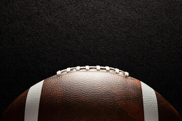 American football ball on dark textured background with space for text.