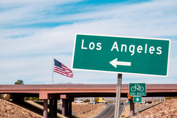 Road sign pointing to Los Angeles with USA flag in the background. California, USA © Karlis