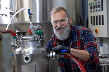 Mature man in protective eyeglasses working on a factory equipment