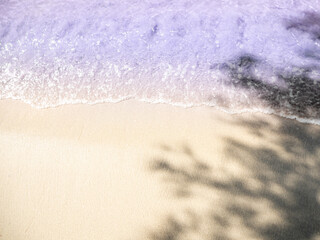 Views of beautiful turquoise waves and sand with shade trees on the beach.