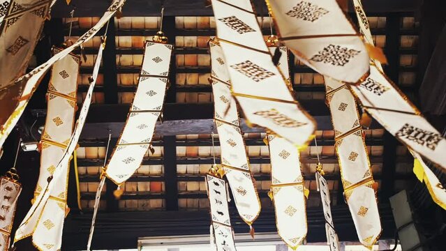 Many white ribbons with gold ornaments flutter in the wind in a Buddhist temple in Southeast Asia. Buddhist symbols Tung Lanna style decorations.