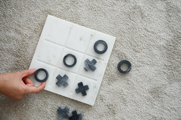 Marble Tic Tac Toe or OX board game. Top view of women hand hold o object playing tic tac toe game....