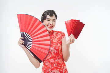 Portrait of young attractive Chinese woman smiling happily holding big red fan, ang pao, red envelopes wearing cheongsam looking confident, celebrate Chinese lunar new year, festive season holiday .