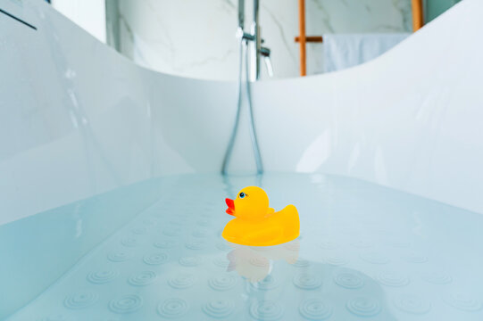 Yellow playful rubber duck float in the bathtub. Kids bath time concept. Funny toy for kits.