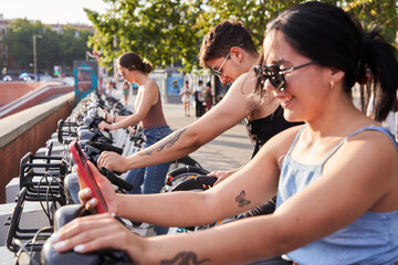 Group of tourists renting a bicycle with the mobile phone to visit the city. Concept of city life