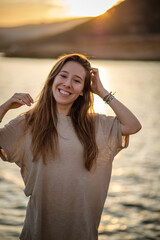 Young girl in the sunset at the seaside smiling at the camera with the ocean behind