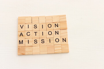 The words vision, action and mission written on wooden cubes over white background