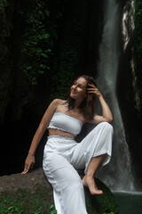 view of beautiful woman in white dress bathing and relaxing in  waterfall