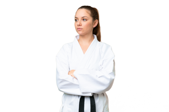 Young blonde woman over isolated chroma key background doing karate keeping the arms crossed