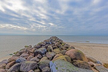 View of a breakwater made of stones out to the sea in the evening at twilight