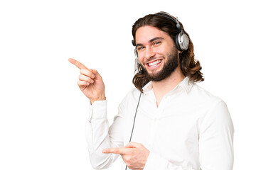 Telemarketer man working with a headset over isolated chroma key background pointing finger to the...