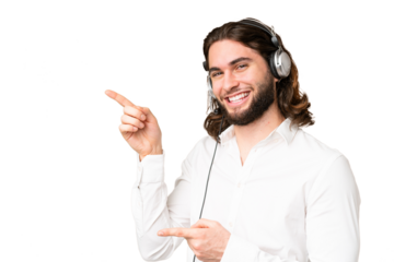 Telemarketer man working with a headset over isolated chroma key background pointing finger to the side and presenting a product