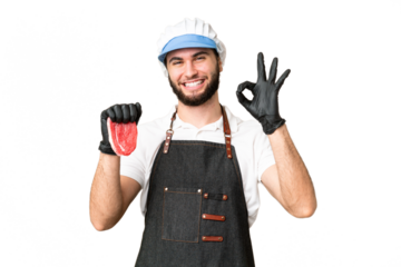 Butcher man wearing an apron and serving fresh cut meat over isolated chroma key background showing ok sign with fingers