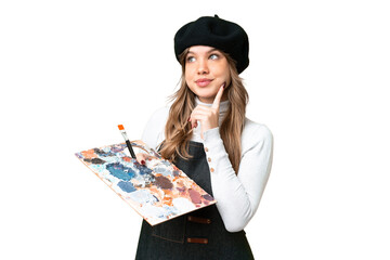 Young artist girl holding a palette over isolated chroma key background thinking an idea while looking up