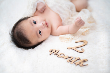 笑顔でカメラ目線をしてマンスリーフォトを撮られる生後2か月の赤ちゃん