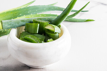 slices of fresh juicy aloe vera in a marble white mortar for the preparation of a cosmetic natural remedy at home. foreground.