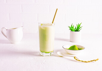 natural matcha lathe green tea in a straw glass on a marble white table against a brick wall. Detox. proper nutrition.