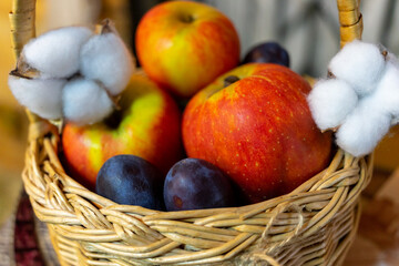 Ripe apples and plums in a vine basket close-up. Selective focus