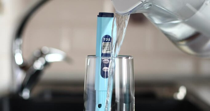 A person takes a filter with water and pours it into a glass with a tds meter to check the water quality. The concept of checking the suitability of water for drinking. 