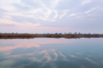 Pink river after sunset, perfect reflection of pink sky in calm surface of the water, countryside background.  Peaceful Ukraine.