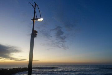 Obraz premium Lampadaire allumé le soir en front de mer au coucher du soleil
