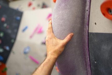 Hand on a lila boulder in a indoor boulder hall.