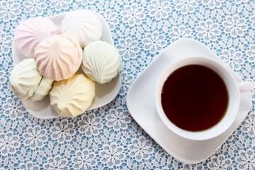 Traditional delicious brewed tea in a cup and air marshmallows lie on table, a sweet dessert. Tea party time.