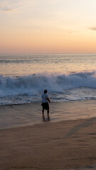 Naklejka premium Young man walking on the shore of the beach in costas de oaxaca at sunset