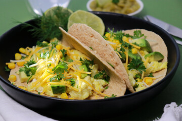 close up of keto tortilla breakfast with scrambled eggs, avocado, cheese and cilantro 