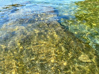 Fototapeta na wymiar Gravel pebbles beach. Crystal clear sea water. Transparent calm sea.