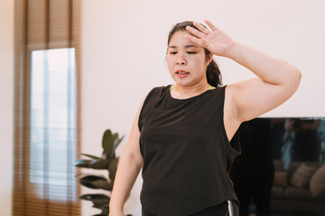chubby woman break exercise wipe sweat exhausted in living room. tired chubby woman rest from workout activity healthy concept wipe sweat face. tired fat exerciser have rest raise hand for sweaty face