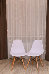 two white chairs against the background of curtains