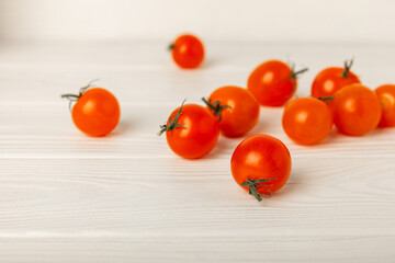 Red cherry tomatoes on white texture wood. Autumn vegetables. Harvesting. Place for text. copy space