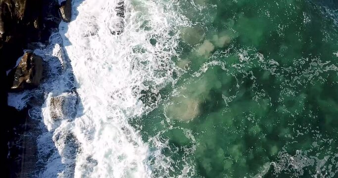 Top down capture over crashing waves at the edge of coastal tide pools during early morning at high tide in La Jolla, California