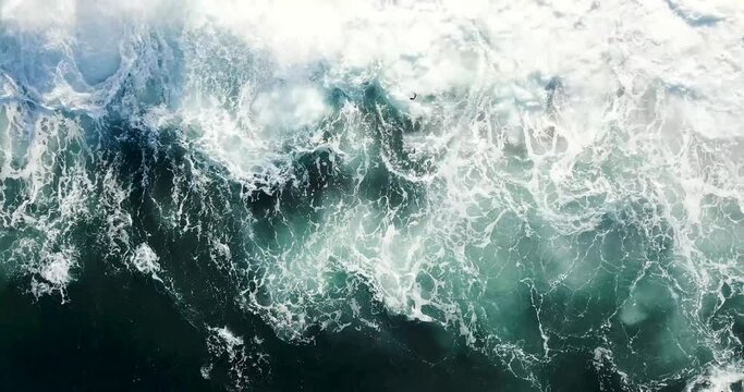 Aerial spin into abstract waves crashing undulating onto rocky outcrops 
