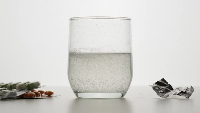 M&eacute;dicament pr&ecirc;t &agrave; boire dans un verre d'eau avec des bulles sur fond blanc