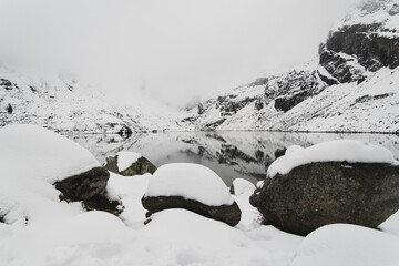 Widok na staw w Tatrach Polskich w zimowej aurze z dużą ilością śniegu.