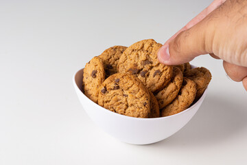 picking up cookies from white bowl on white background, isolated.