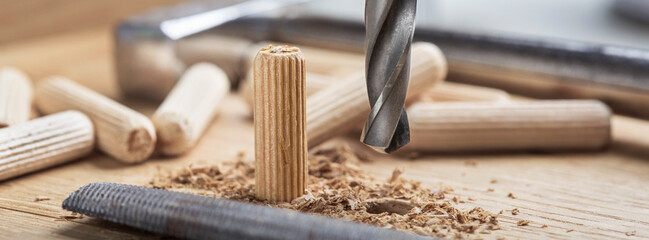 drill bit makes hole in wooden oak board for wooden dowel.