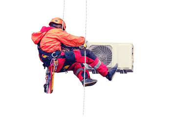 A male worker in a red uniform installs an air conditioner in a niche under the window, isolated on a white background