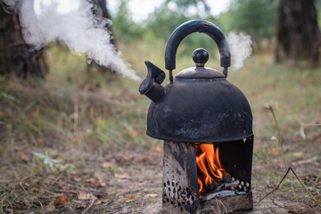 Cooking tea in a kettle on a campfire using a mobile stove. Rest at nature.