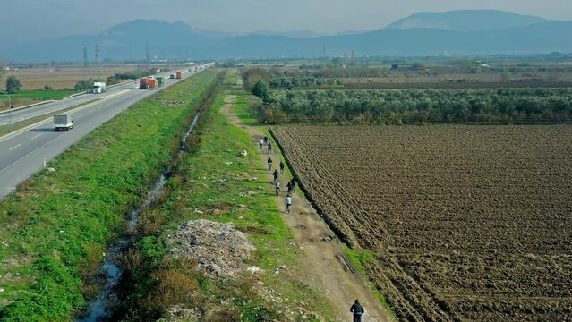 drone view of people cycling on forest road in town