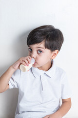 Cute boy in white shirt on white background - drinking fermented milk