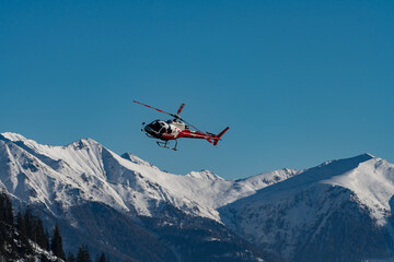 Fototapeta na wymiar A helicopter taken in flight in front of a snowy mountain panorama