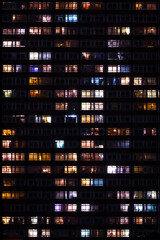 Fototapeta premium Residential tower apartment windows light up at night flat on - Portrait 