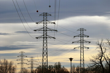 Duże słupy energetyczne z przewodami elektrowni dostarczają prąd elektryczny do miasta - obrazy, fototapety, plakaty