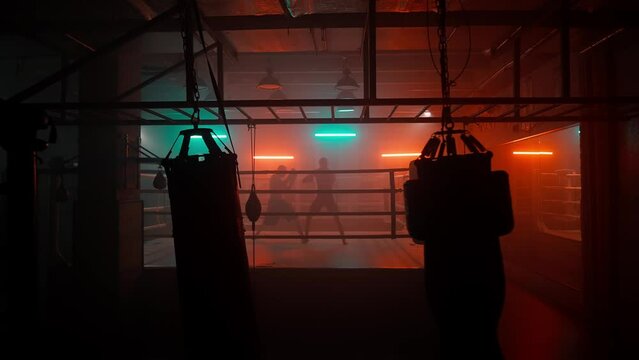 Boxer in the boxing gym. Bandages his hands. Sparring in the ring. Boxer jumping rope. Exercise with ropes. Round one. Fog in the ring. Zetsky sport. Beautiful backlight. World boxing champion.

