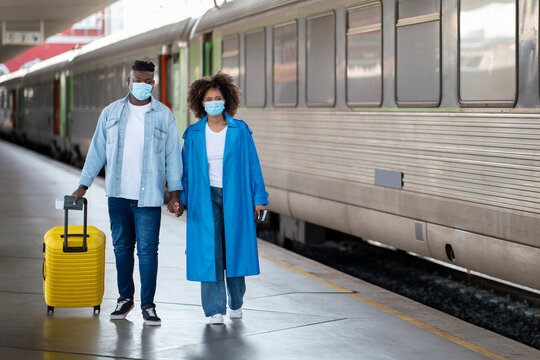 Young Black Couple Wearing Medical Masks Walking With Suitcase At Railway Station